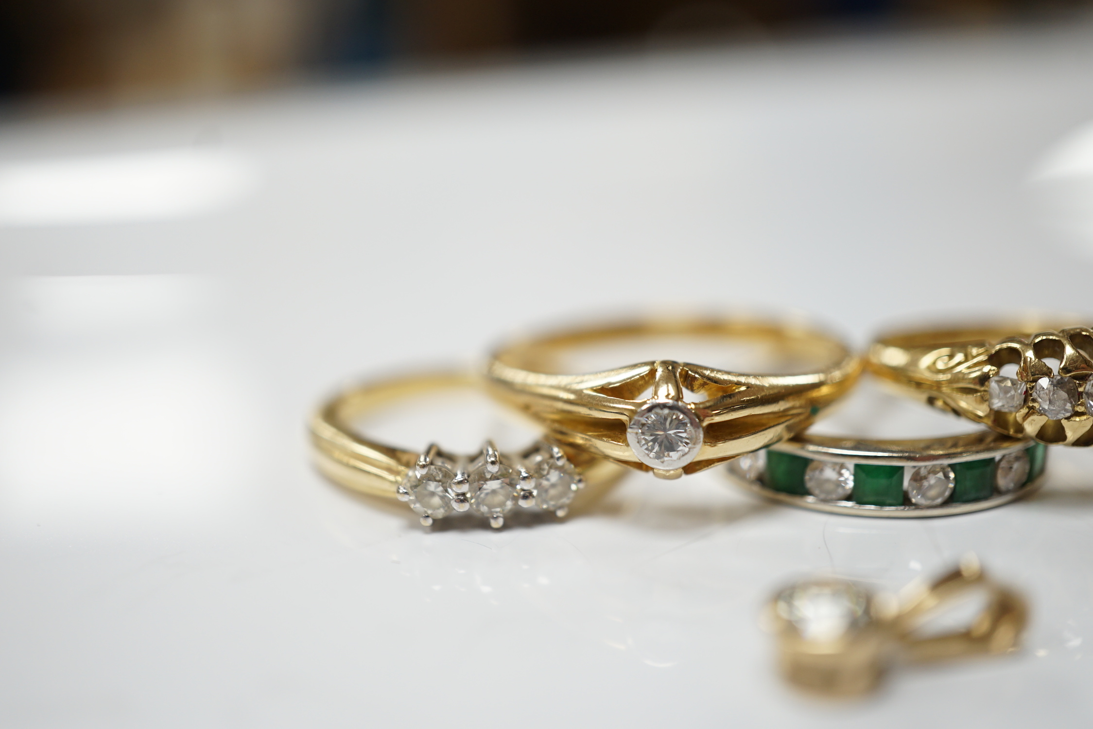 Four assorted early 20th century and later 18ct and gem set rings, including solitaire diamond and three stone diamond, gross 14.6 grams, together with a white metal and channel set emerald and diamond half hoop ring and